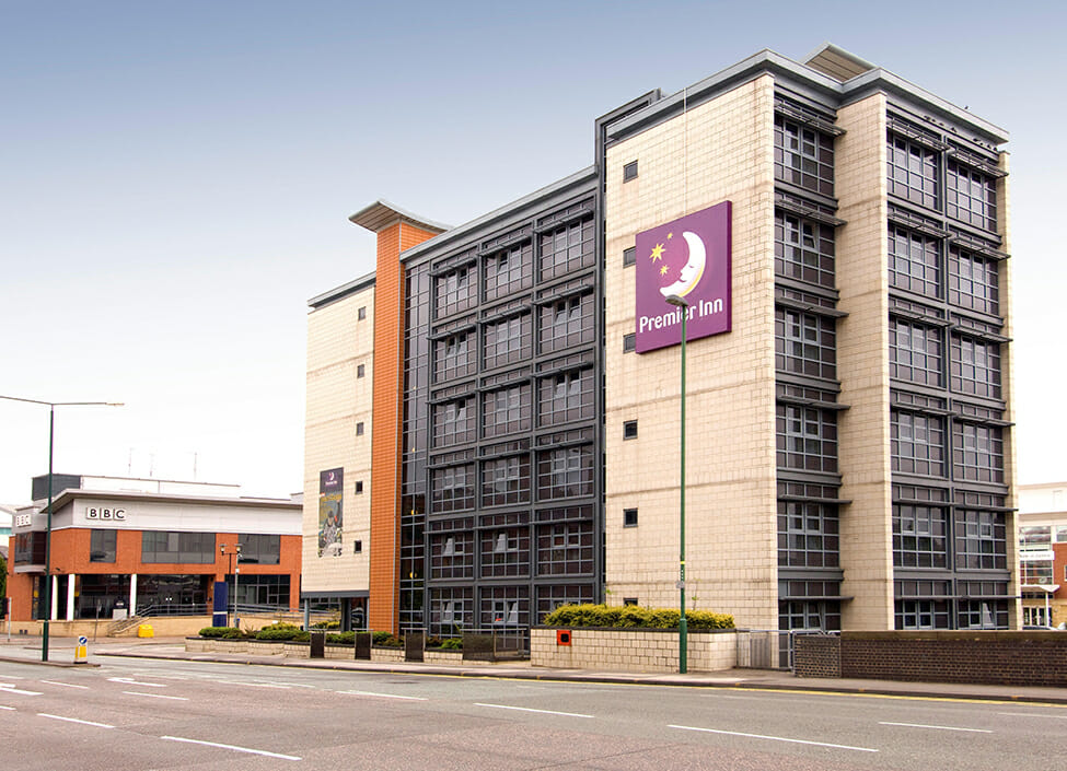 Premier Inn Nottingham Arena hotel during the day situated next to a quiet road with another building next door